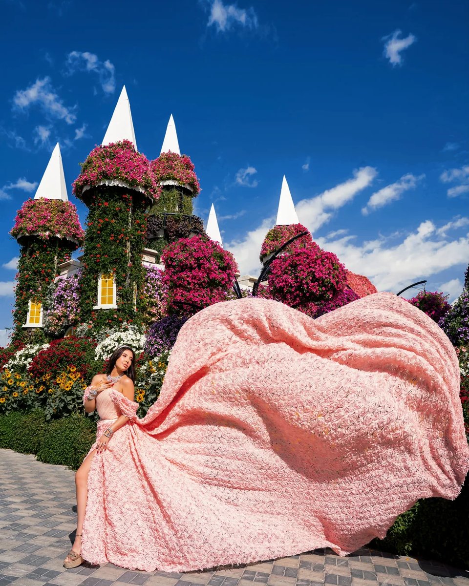 Pink rosette dress lifted mid-air before floral castle spires at Miracle Garden