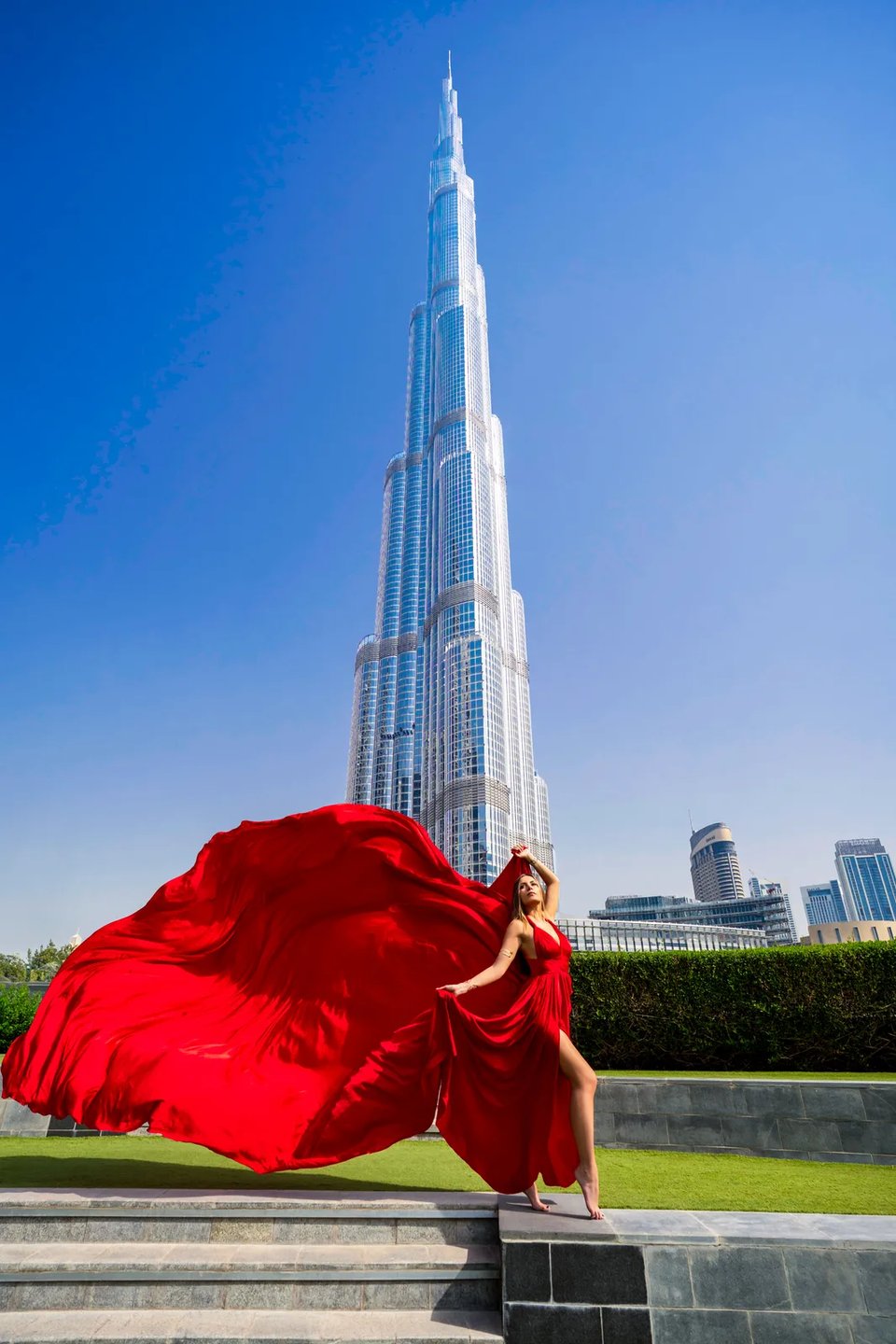 Vast red fabric sweeping sideways on a lawn beneath the Burj Khalifa